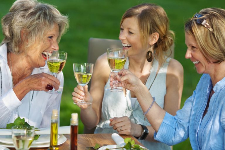 Happy family toasting white wine at dining table in lawn Happy family toasting white wine at dining table in lawn