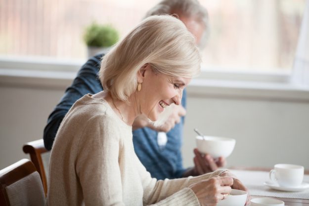 Happy senior woman having breakfast with aged husband at home