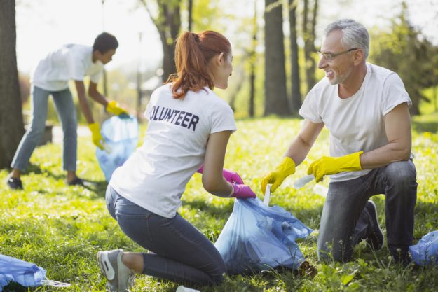 Non profit volunteer. Vigorous two volunteers holding garbage bag and chatting
