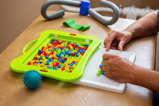 close male physiotherapist massaging leg patient physio room