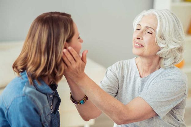 delighted loving senior woman holding cheeks of her daughter delighted loving senior woman holding cheeks of her daughter