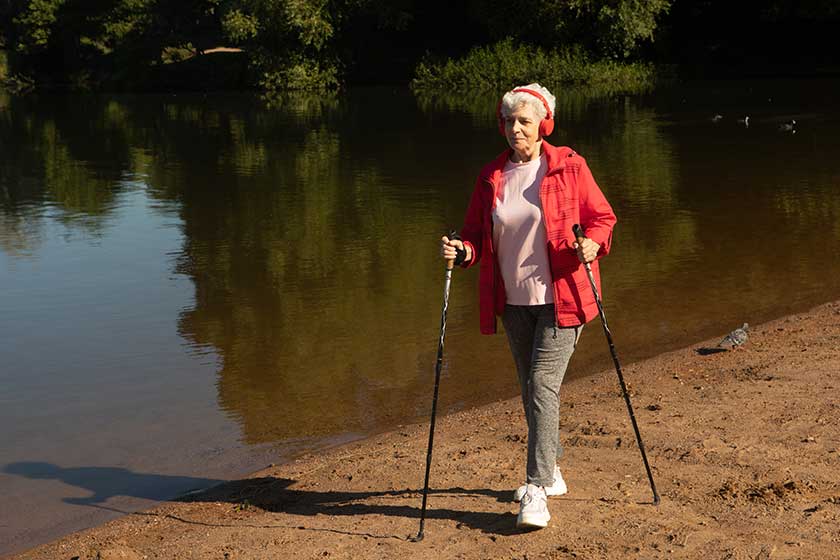 grey haired woman wearing red jacket walking tracking sticks beach grey haired woman wearing red jacket walking tracking sticks beach