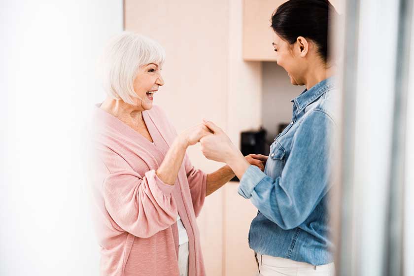 happy grandmother and adult granddaughter having fun at home