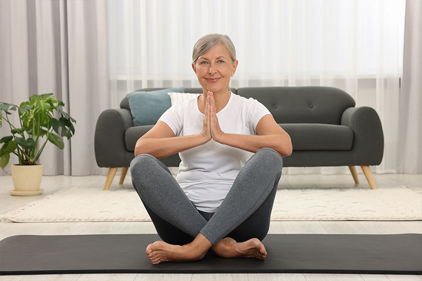 Happy senior woman practicing yoga on mat Happy senior woman practicing yoga on mat