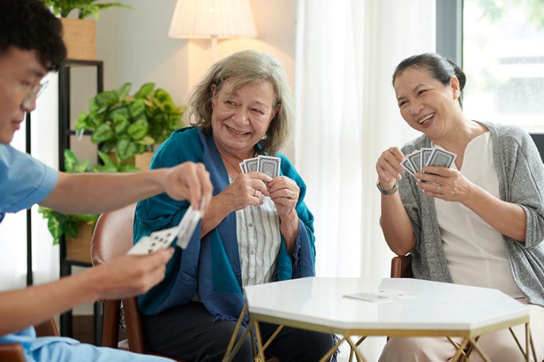 joyful senior women looking nursing home nurse choosing playing card