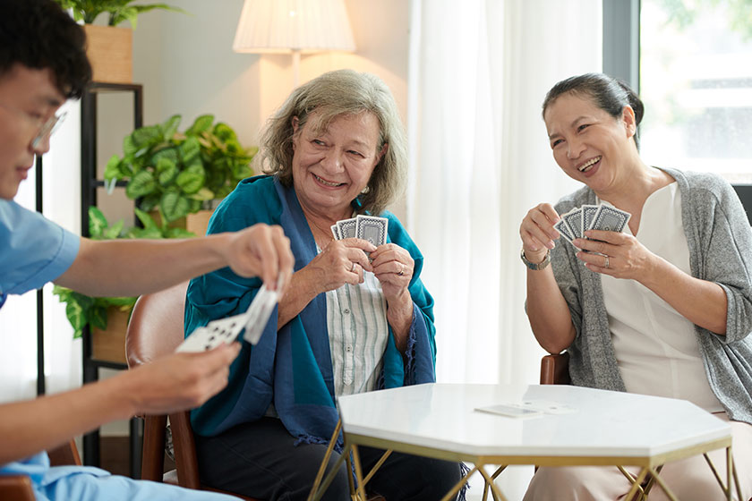 joyful senior women looking nursing home nurse choosing playing card