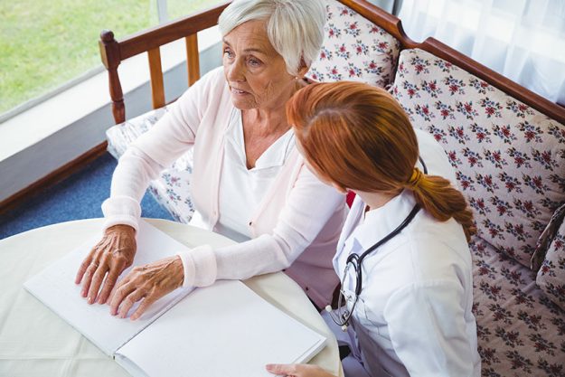 nurse helping senior woman with braille