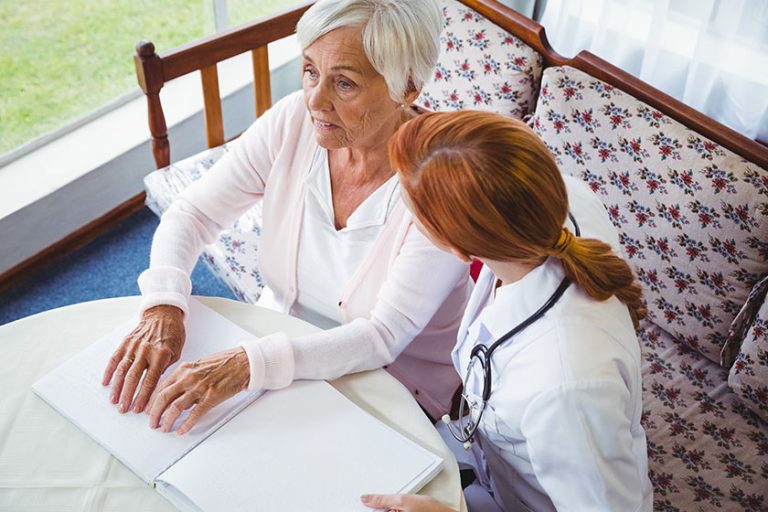 nurse helping senior woman with braille nurse helping senior woman with braille