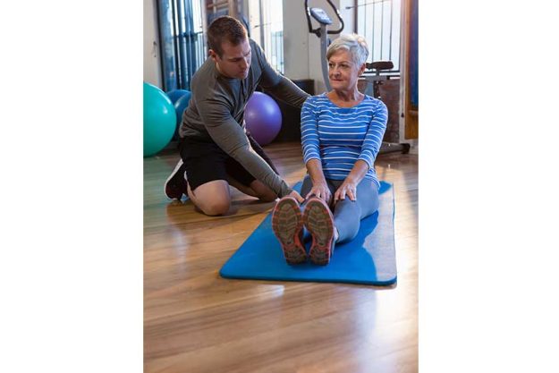 physiotherapist assisting senior woman in exercis