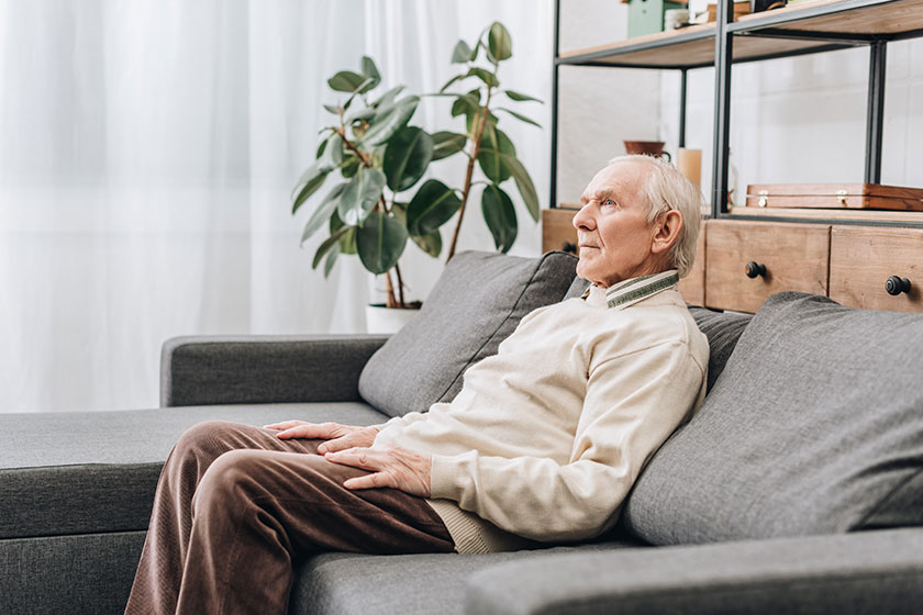 Retired man with grey hair sitting on sofa Retired man with grey hair sitting on sofa