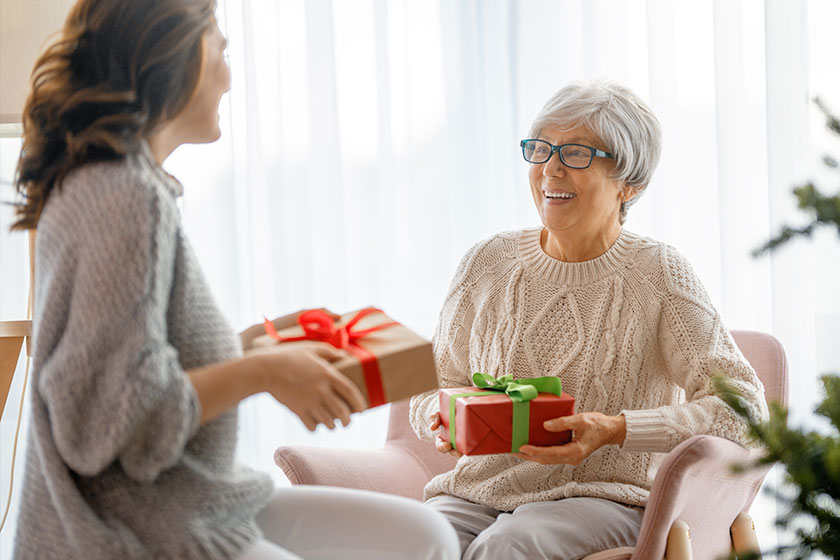 Senior mom and her adult daughter exchanging gifts