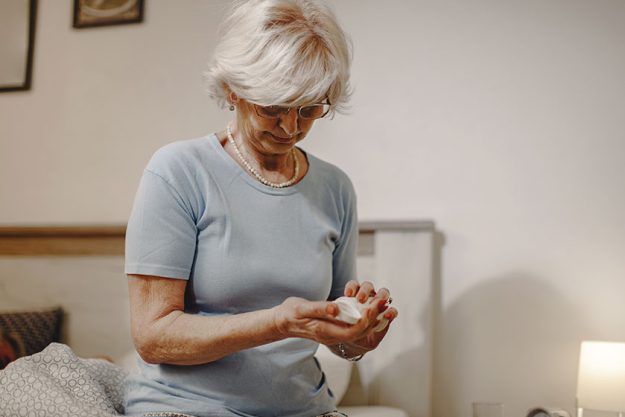 senior woman sitting bed taking medicine evening