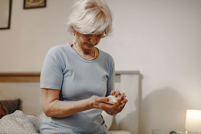 senior woman sitting bed taking medicine evening