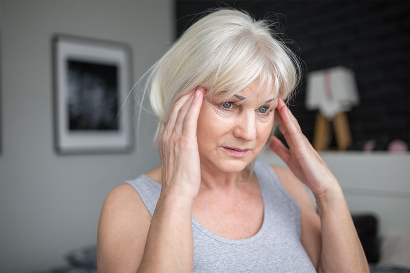Senior woman with headache holding hands on temples