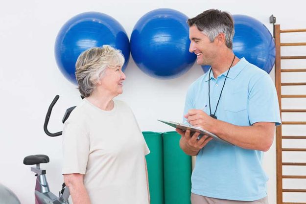 trainer writing on clipboard with senior woman