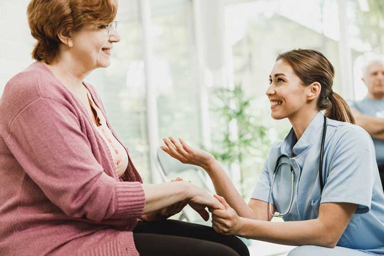 young nurse senior woman holding hands while talking waiting room young nurse senior woman holding hands while talking waiting room