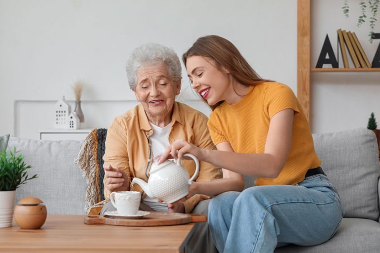 young woman pouring tea cup her grandmother home