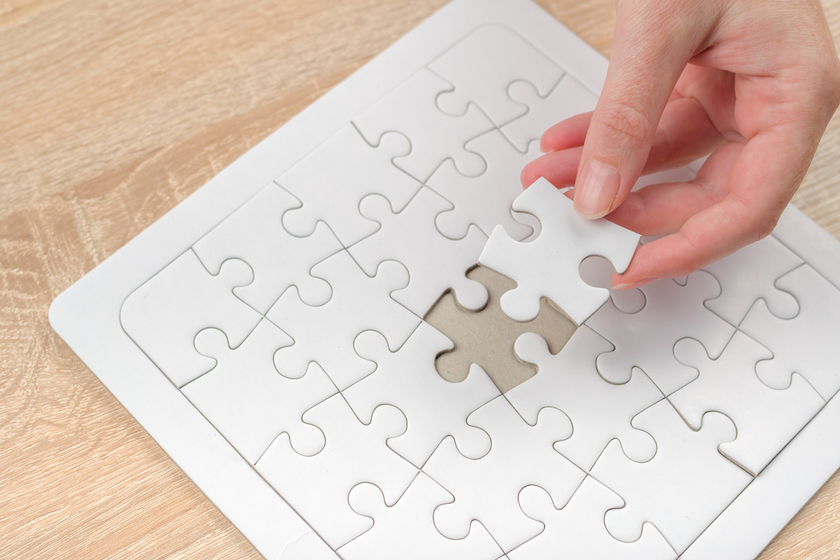 Female hand putting a missing piece into jigsaw puzzle