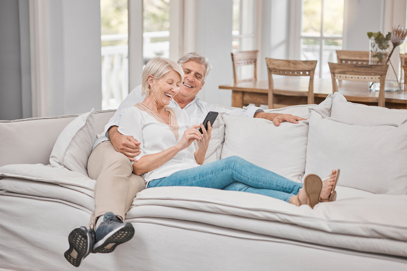 Were definitely two of a kind. a elderly couple using a cellphone at home.