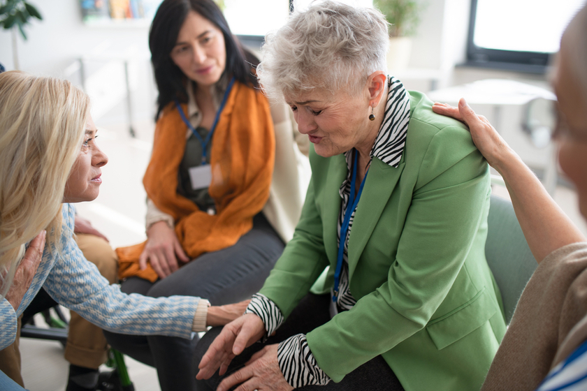 Group of senior people sitting in circle during therapy session, consoling depressed woman. Group of senior people sitting in circle during therapy session, consoling depressed woman.