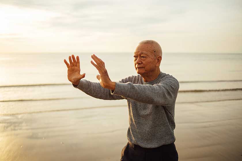 Asian senior old man practice tai chi and yoga pose on the beach Asian senior old man practice tai chi and yoga pose on the beach