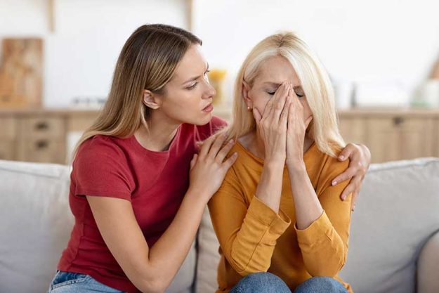Caring grownup daughter comforting frustrated unhappy senior woman hugging sitting