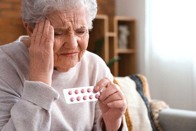 Ill senior woman pills home closeup