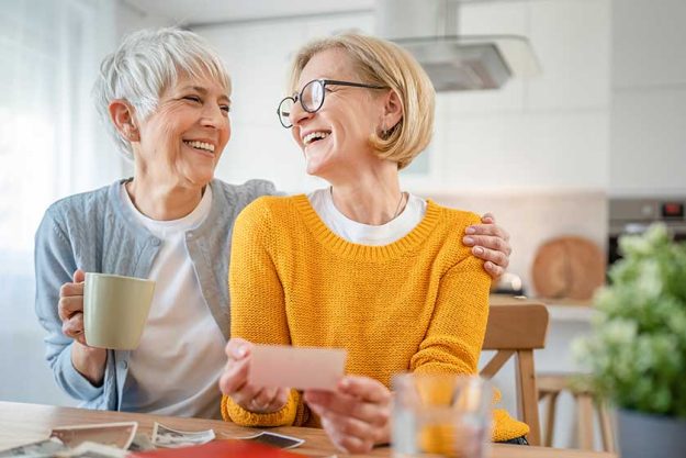 Senior mature women friends sisters looking family photos album two