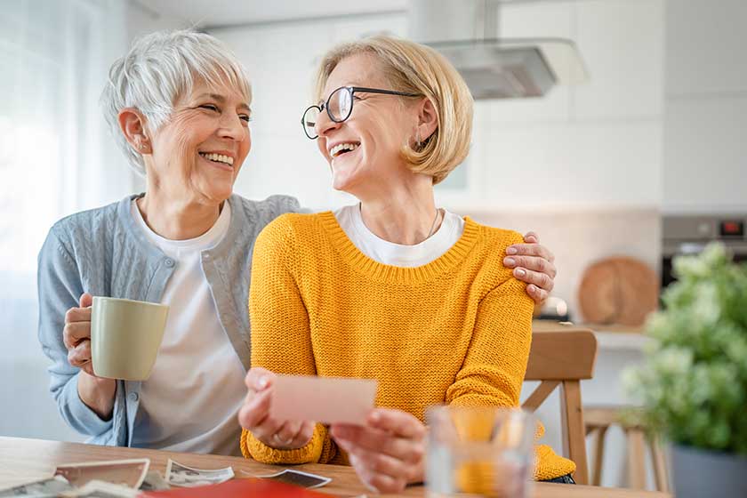 Senior mature women friends sisters looking family photos album two