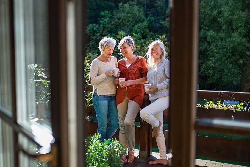 Senior women friends standing outdoors on terrace resting