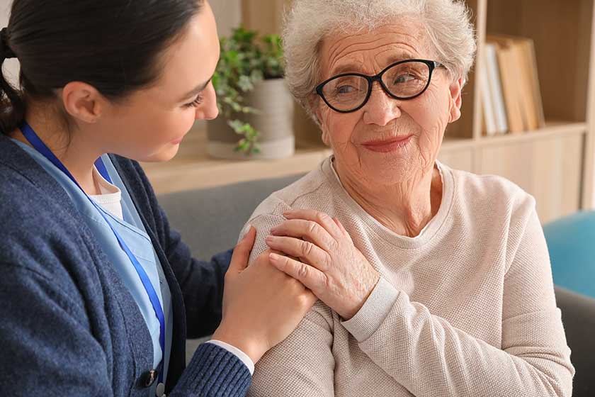 Young caregiver hugging senior woman home closeup