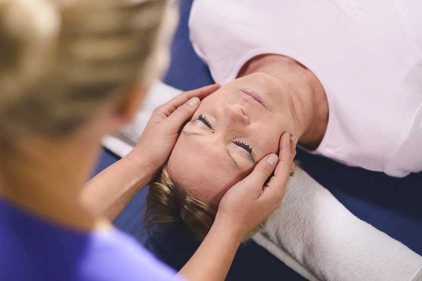 Young therapist doing reiki therapy to senior woman