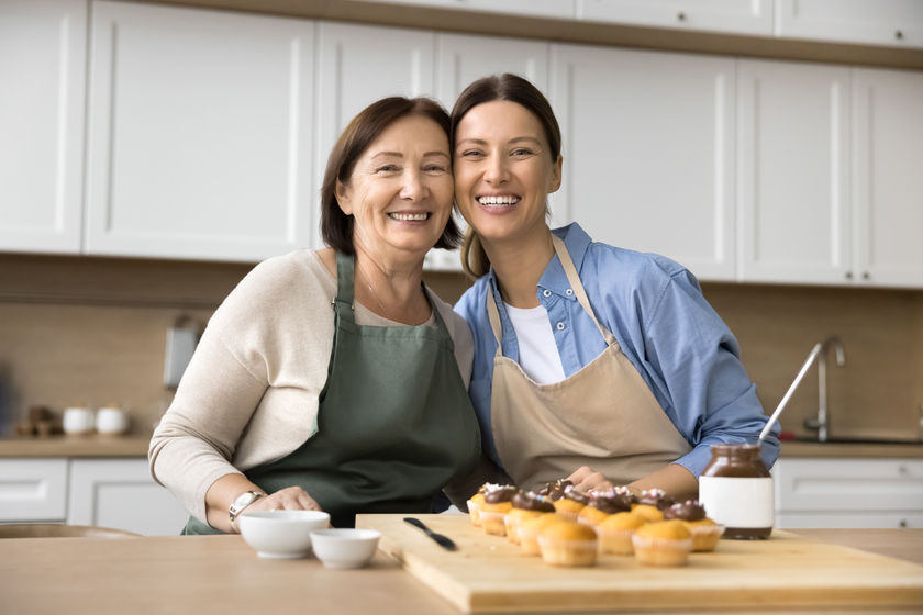 Happy senior mom and adult child preparing homemade dessert