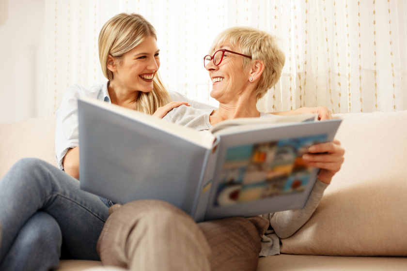Mother and daughter having a great time while looking through old family photo album. Looking at each other. Happy family moments at home