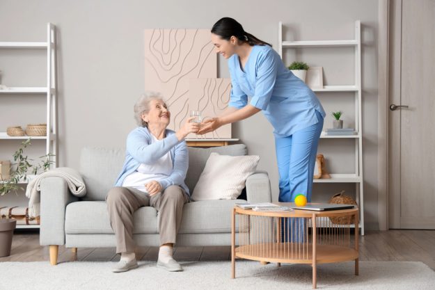 Senior woman taking glass of water from physical therapist at home