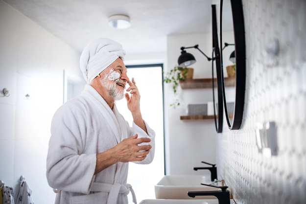 A senior man doing morning routine in bathroom indoors at home copy space