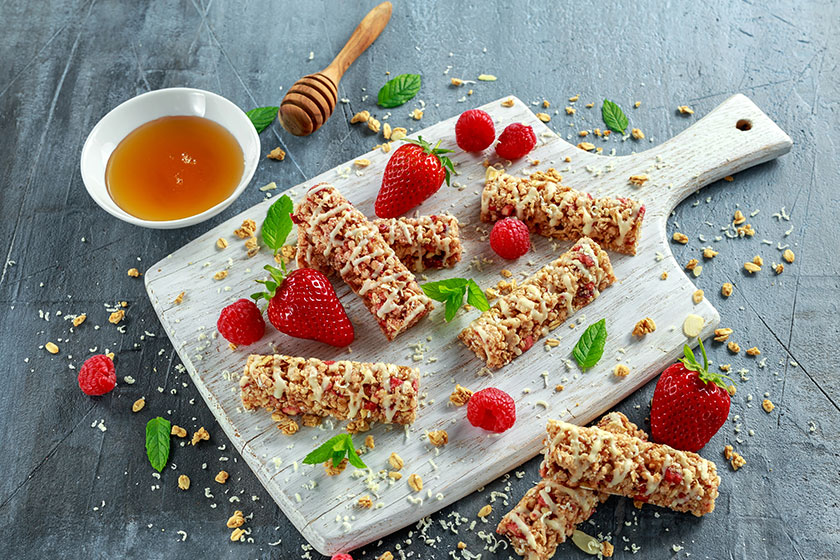 Granola bar with strawberries raspberry honey and white chocolate on cutting board