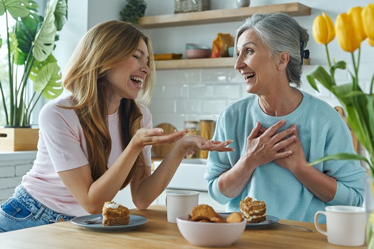Happy mother her adult daughter communicating while enjoying sweet food