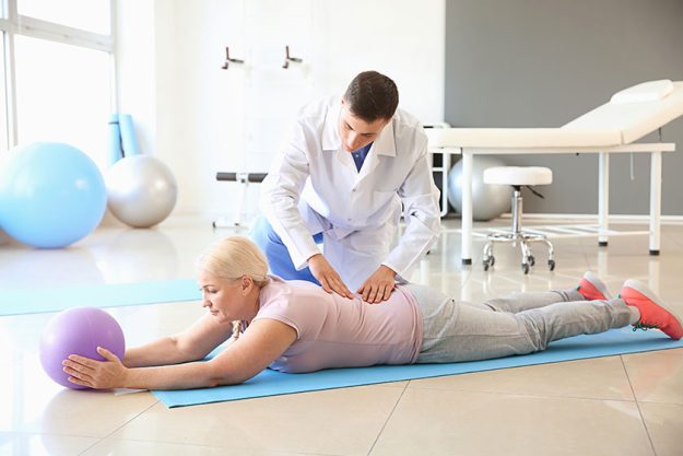 Physiotherapist working with mature patient in rehabilitation center