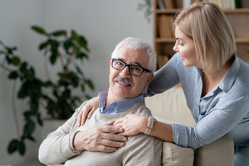 Restful senior man couch holding hand his young blonde daughter Restful senior man couch holding hand his young blonde daughter