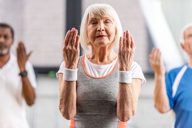 Selective focus senior sportswoman closed eyes making exercise gym