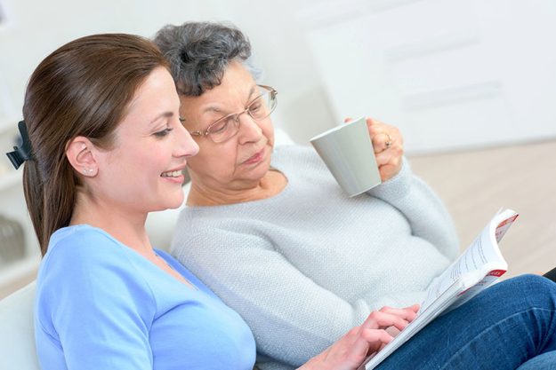 Senior lady and younger lady looking at a book together