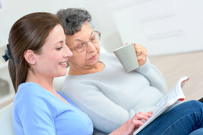 Senior lady and younger lady looking at a book together Senior lady and younger lady looking at a book together