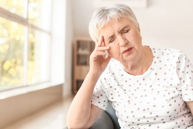 Stressed senior woman suffering headache home