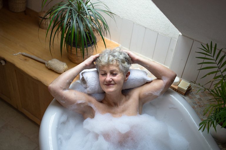 Top view of contented senior woman lying in bath tub at home eyes closed Top view of contented senior woman lying in bath tub at home eyes closed