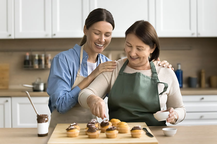 Cheerful positive confectioner mom young adult daughter woman decorating homemade Cheerful positive confectioner mom young adult daughter woman decorating homemade