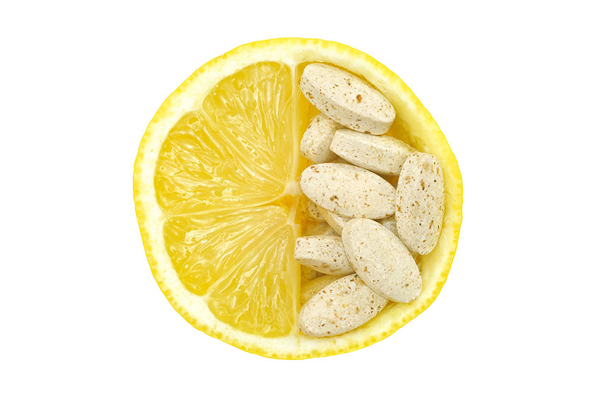 Close up of lemon and pills isolated – vitamin concept