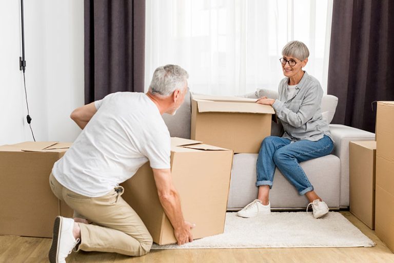 Mature man holding box woman sitting sofa new house Mature man holding box woman sitting sofa new house