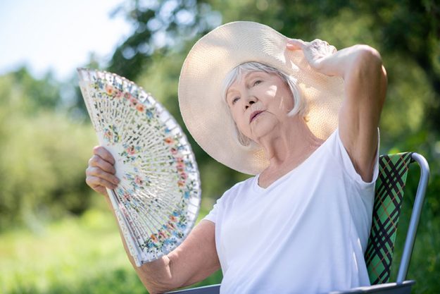 Woman relaxing in a deck chair with a fan