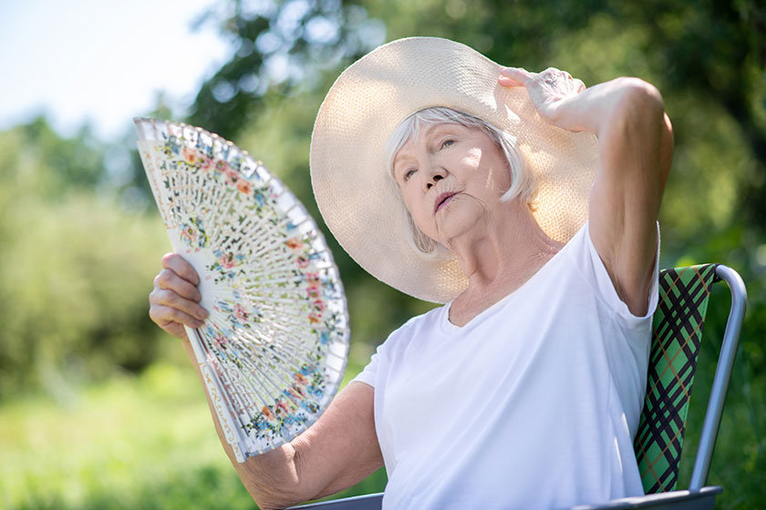 Woman relaxing in a deck chair with a fan